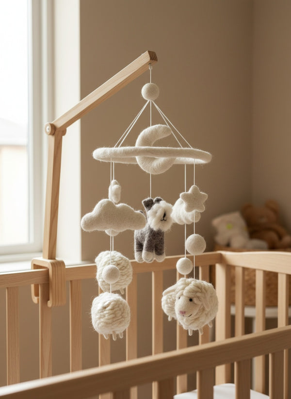 Felt wool baby mobile with schnauzer and sheep hanging above a light wood crib in a bright nursery