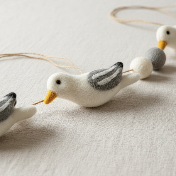Close-up of felt seagull garland on linen, showing the needle felted wool texture in detail