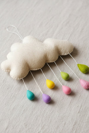 Close-up of pastel felt raindrops on a light linen surface, showing the soft wool felt texture