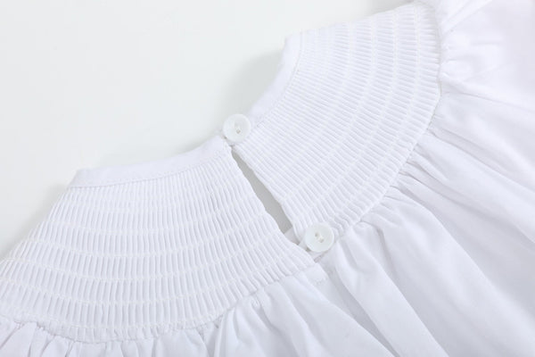 White and pink bows smocked bishop dress for babies, angle view showcasing its charming design and delicate details.