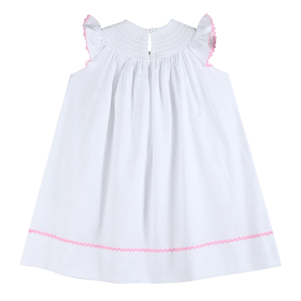 White and pink bows smocked bishop dress for babies, angle view showcasing delicate design and craftsmanship.