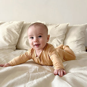 Zippered footie in apricot for babies, perfect for cozy sleep and bedding. Angle 2 view.